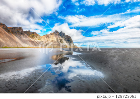 Amazing sunny day and gorgeous reflection of Vestrahorn mountaine on Stokksnes cape in Iceland. Amazing sunny day and gorgeous reflection of Vestrahorn mountaine on Stokksnes cape in Iceland. 128725063