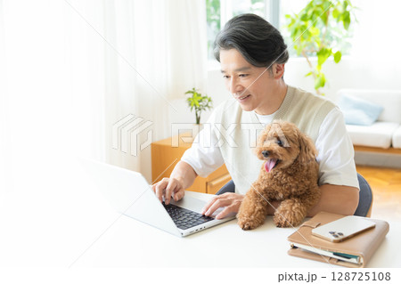 テレワーク　犬を抱っこしながら仕事をする男性 128725108