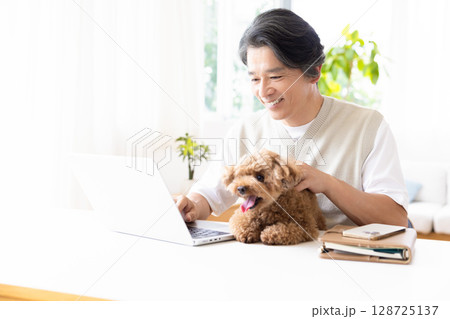 テレワーク 犬を抱っこしながら仕事をする男性 テレワーク 犬を抱っこしながら仕事をする男性 128725137