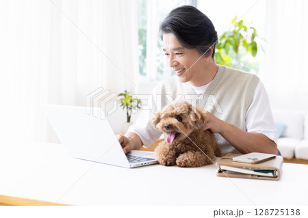 テレワーク　犬を抱っこしながら仕事をする男性 128725138