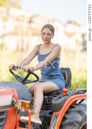 Young woman driving tractor in countryside Young woman driving tractor in countryside 128725352