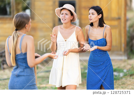 Three young women neighbors quarrel and swear in rural yard Three young women neighbors quarrel and swear in rural yard 128725371