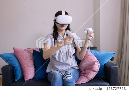 家のリビングでVRゴーグルを付けて仮想現実を楽しむ日本人女性 128727728
