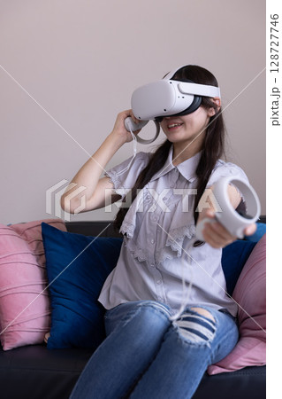 家のリビングでVRゴーグルを付けて仮想現実を楽しむ日本人女性 家のリビングでVRゴーグルを付けて仮想現実を楽しむ日本人女性 128727746