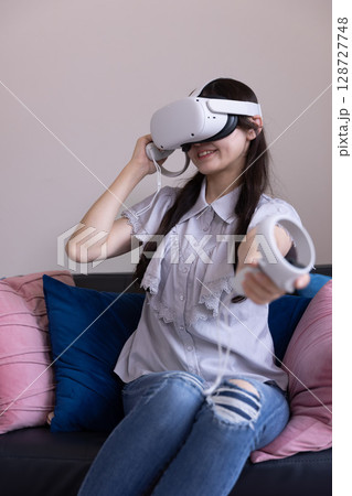 家のリビングでVRゴーグルを付けて仮想現実を楽しむ日本人女性 家のリビングでVRゴーグルを付けて仮想現実を楽しむ日本人女性 128727748