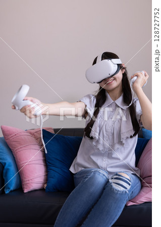家のリビングでVRゴーグルを付けて仮想現実を楽しむ日本人女性 家のリビングでVRゴーグルを付けて仮想現実を楽しむ日本人女性 128727752