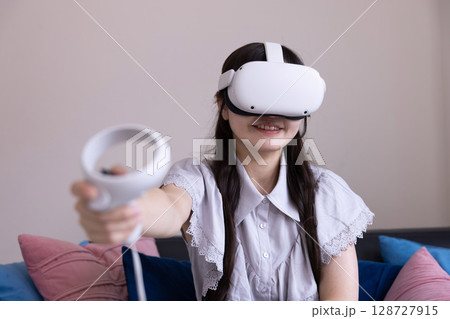 家のリビングでVRゴーグルを付けて仮想現実を楽しむ日本人女性 家のリビングでVRゴーグルを付けて仮想現実を楽しむ日本人女性 128727915