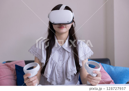 家のリビングでVRゴーグルを付けて仮想現実を楽しむ日本人女性 128727937
