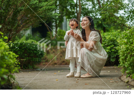 happy mother and toddler girl with Ruellia simplex or Mexican petunia flower in garden 128727960