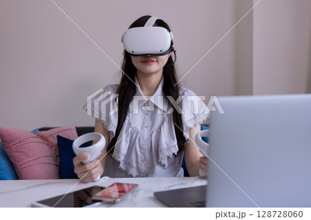家のリビングでVRゴーグルを付けて仮想現実を楽しむ日本人女性 128728060