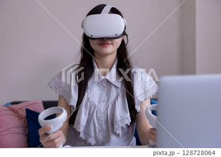 家のリビングでVRゴーグルを付けて仮想現実を楽しむ日本人女性 家のリビングでVRゴーグルを付けて仮想現実を楽しむ日本人女性 128728064