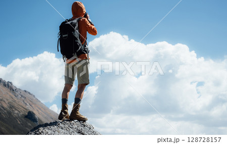 Woman photographer taking picture on high altitude mountain top,with a lake in the distance 128728157