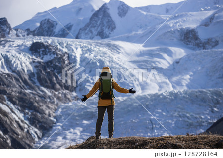 Backpacking woman open arms to the large hanging glacier on high altitude mountain top Backpacking woman open arms to the large hanging glacier on high altitude mountain top 128728164