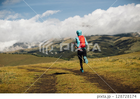 Fitness woman runner running at high altitude grassland mountain top road Fitness woman runner running at high altitude grassland mountain top road 128728174