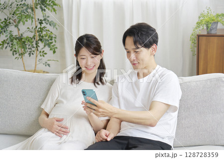 リビングでスマホを使う妊娠中の妻と夫 128728359
