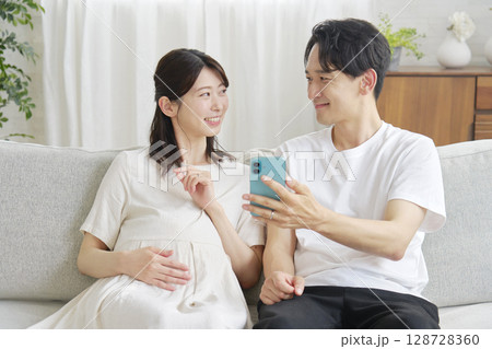 リビングでスマホを使う妊娠中の妻と夫 128728360