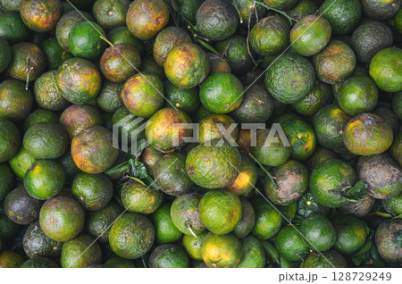 background with ripe green oranges. Tropical fresh fruits on the counter in market in Asia in Vietnam 128729249