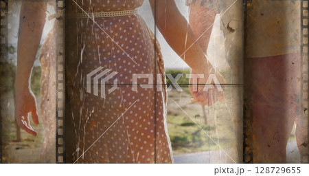 Walking couple wearing brown polka dot dress and red shorts on sunlit rural path, filmstrip overlay Walking couple wearing brown polka dot dress and red shorts on sunlit rural path, filmstrip overlay 128729655