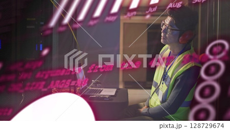 Monitoring tech wearing neon yellow vest with red earmuffs using laptop in server room, copy space 128729674
