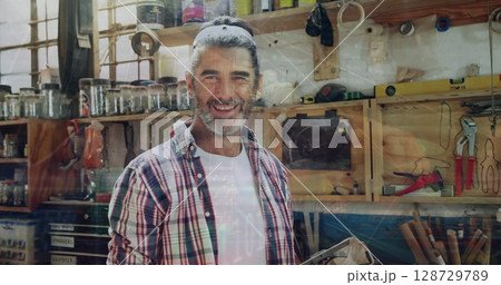 Reviewing woodworking project, man with ponytail holding tablet in workshop, with jars and clamps 128729789