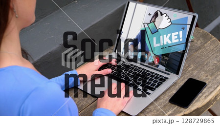 Adult Korean man typing on laptop on outdoor terrace, with LIKE overlay and smartphone, copy space 128729865