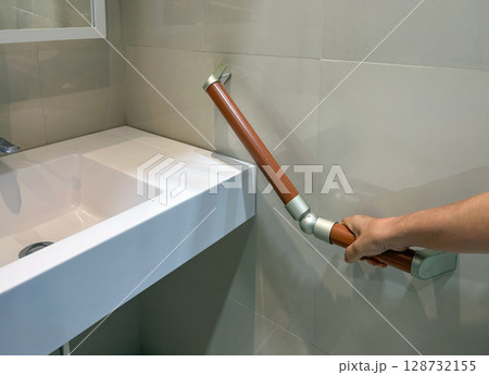 Senior woman holding on handrail for safety in bathroom Senior woman holding on handrail for safety in bathroom 128732155