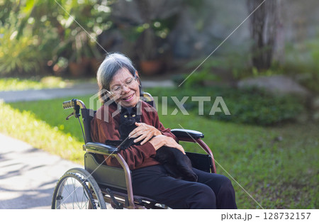 Elderly asian woman holding baby black cat in backyard. 128732157