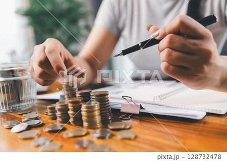 Businesswoman saving money with piggy bank and coins on desk, financial planning and investment concept. Young Asian woman making stack of coin. invest save finance concept, saving money, investment 128732478