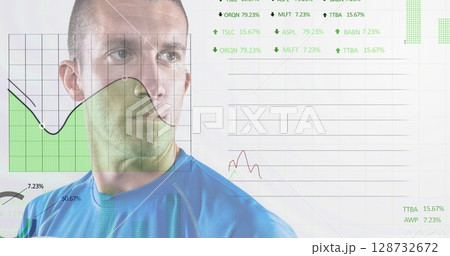 Standing adult man wearing blue top in studio, viewing green shaded chart and line graphs 128732672