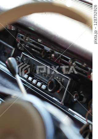 The dashboard of a vintage classic car features detailed analog gauges, a radio, and air vents in polished wood and chrome, offering a fresh yet luxurious look. The dashboard of a vintage classic car features detailed analog gauges, a radio, and air vents in polished wood and chrome, offering a fresh yet luxurious look. 128732926