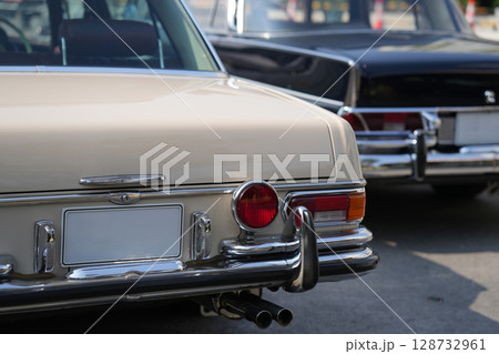 A chrome keyhole above the license plate and a polished rear trunk lock system on a vintage car highlight its sturdy and secure mechanical design. A chrome keyhole above the license plate and a polished rear trunk lock system on a vintage car highlight its sturdy and secure mechanical design. 128732961