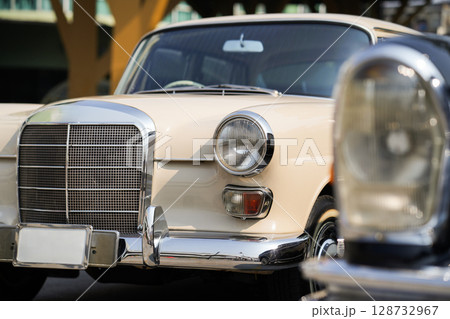 The round headlights and side turn signals on classic cars, framed in polished chrome, highlight the vintage style with old-fashioned lighting and curved fender details. The round headlights and side turn signals on classic cars, framed in polished chrome, highlight the vintage style with old-fashioned lighting and curved fender details. 128732967
