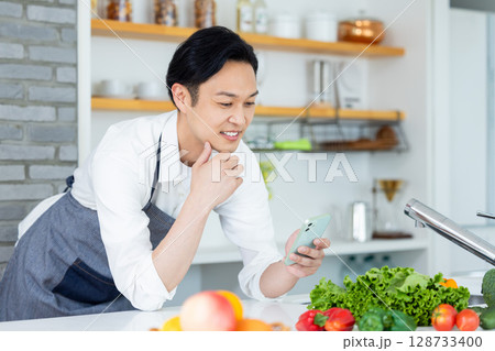 キッチン　スマホを見ている男性 128733400