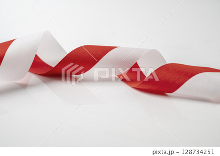 The striped red and white ribbon of the Indonesian flag on a white background. Concept of Indonesian Independence Day or Kemerdekaan 128734251