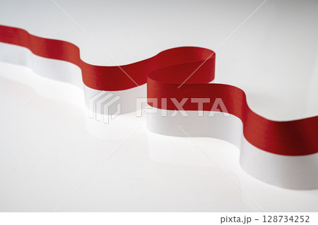 The striped red and white ribbon of the Indonesian flag on a white background. Concept of Indonesian Independence Day or Kemerdekaan 128734252