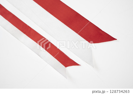 The striped red and white ribbon of the Indonesian flag on a white background. Concept of Indonesian Independence Day or Kemerdekaan 128734263