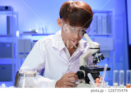 Young scientist looking through a microscope in the laboratory. 128735476