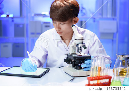 Scientist recording the results of the study in a laboratory journal. Scientist recording the results of the study in a laboratory journal. 128735542