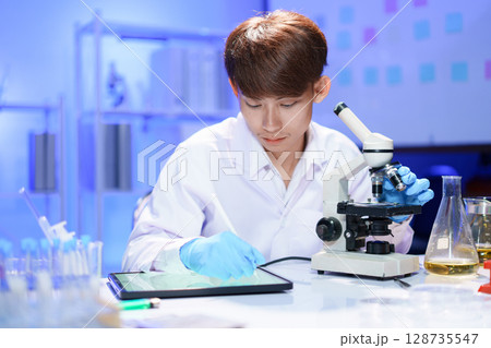 Scientist recording the results of the study in a laboratory journal. 128735547
