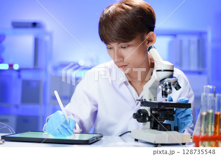 Scientist recording the results of the study in a laboratory journal. Scientist recording the results of the study in a laboratory journal. 128735548