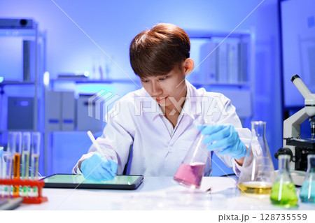 Scientist recording the results of the study in a laboratory journal. 128735559