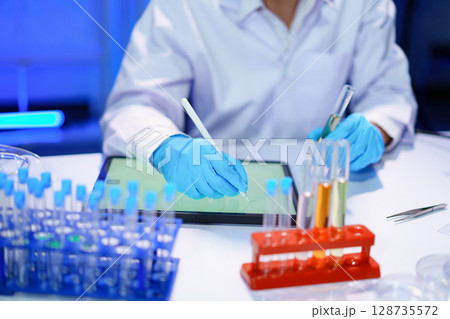 Scientist recording the results of the study in a laboratory journal. Scientist recording the results of the study in a laboratory journal. 128735572