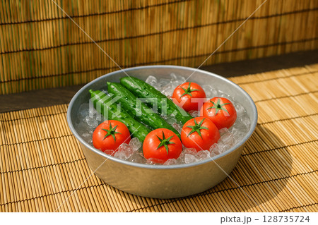 たらいで冷やされた採れたてのトマトときゅうり 128735724