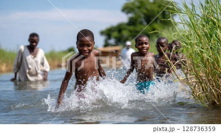 Joyful african boys splashing and playing in river on a sunny day. 128736359