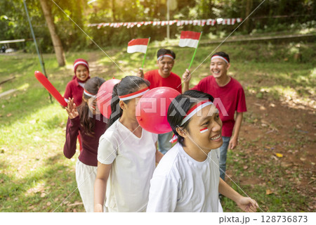 Portrait of an Indonesian southeast asian people celebrate Indonesia Independence Day on the 17th of August with a game of keep the balloon from blowing out outdoors. Concept of Kemerdekaan Indonesia Portrait of an Indonesian southeast asian people celebrate Indonesia Independence Day on the 17th of August with a game of keep the balloon from blowing out outdoors. Concept of Kemerdekaan Indonesia 128736873