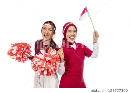 Indonesian southeast asian women celebrating Indonesia Independence Day on the 17th of August by holding the Indonesian national flag isolated over a white background. Concept of Kemerdekaan Indonesia 128737300