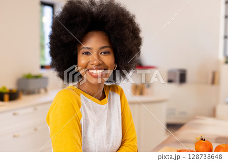 African American woman leaning on kitchen island, smiling and showcasing orange tomatoes in kitchen African American woman leaning on kitchen island, smiling and showcasing orange tomatoes in kitchen 128738648