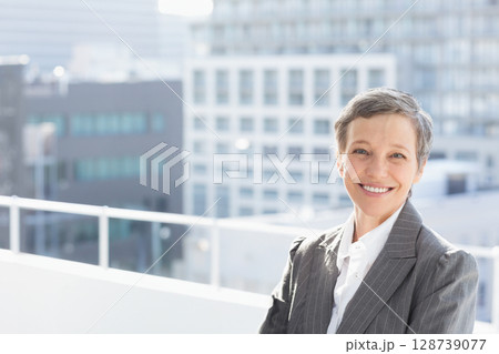 Woman leaning against white metal railing on rooftop deck overlooking office buildings, copy space Woman leaning against white metal railing on rooftop deck overlooking office buildings, copy space 128739077