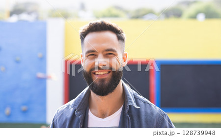 Teenage man standing at playground by colorful wall panels, wearing denim shirt and white T shirt Teenage man standing at playground by colorful wall panels, wearing denim shirt and white T shirt 128739948