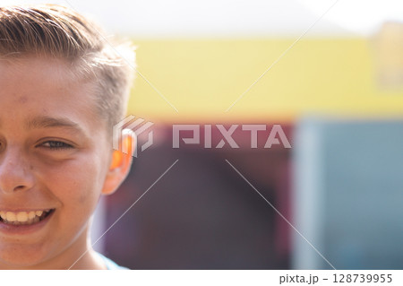 Child girl smiling outdoors in front of building facade with yellow band, showing joy, copy space 128739955